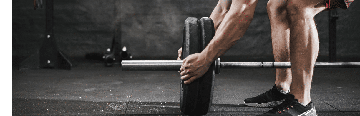 Young athlete preparing barbell for lifting weight at the gym. Magnesia protection dust cloud. Handsome man doing functional training. Practicing powerlifting. Workout exercises.