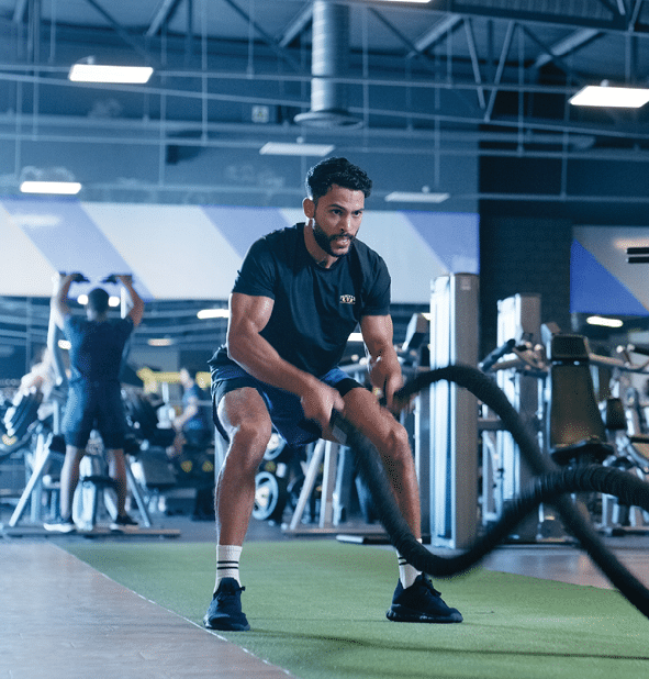 Man, training and rope for workout at gym or warm up to exercise for health, training and determination. Sport, fitness and muscle with commitment, energy and mental wellbeing, wellness with strength