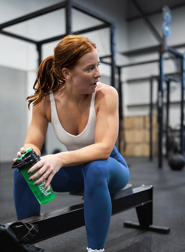 A woman sitting on a bench with a green bottle. Description generated by AI